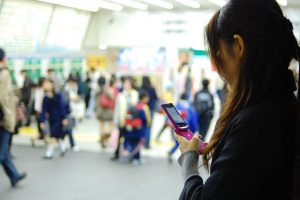 人が行き交う駅でスマホを操作する女性